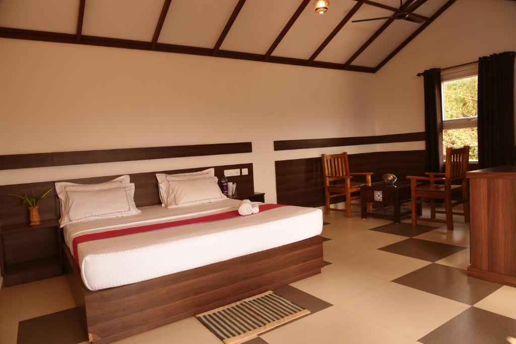 a bedroom with a bed and a table and chairs at Wayanad Village Resort in Koroth
