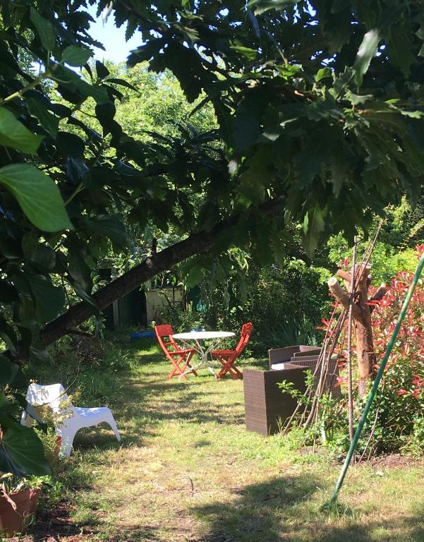 un jardin avec une table et des chaises sous un arbre dans l'établissement Chambre ville & campagne, à Nantes