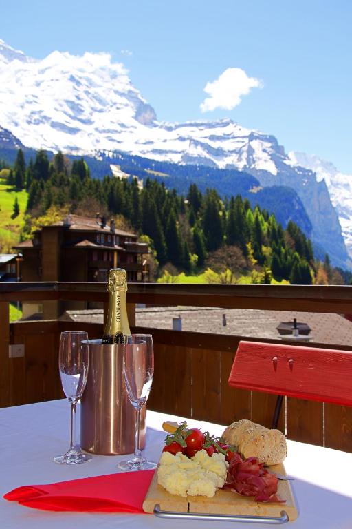 a table with a bottle of wine and two glasses at Chalet Bella Vista 12 - Penthouse in Wengen