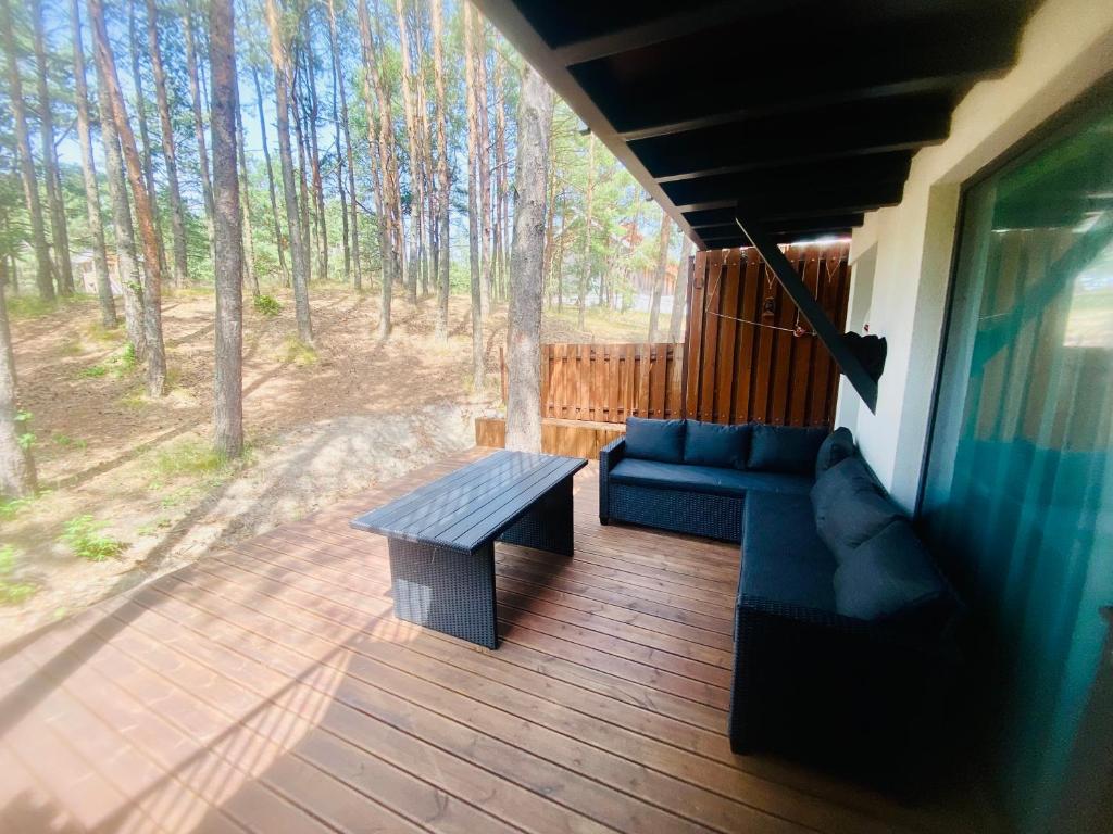 a porch with a couch and a bench on a deck at Poilsis Nidoje -LA ISLA DE NIDA- Su terasa in Nida