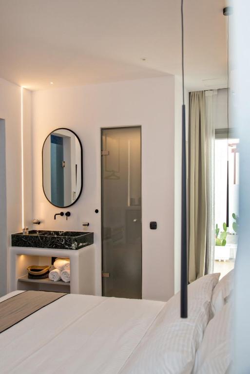 sypialnia z białym łóżkiem i lustrem w obiekcie Levantes Luxury Suites II w mieście Tinos