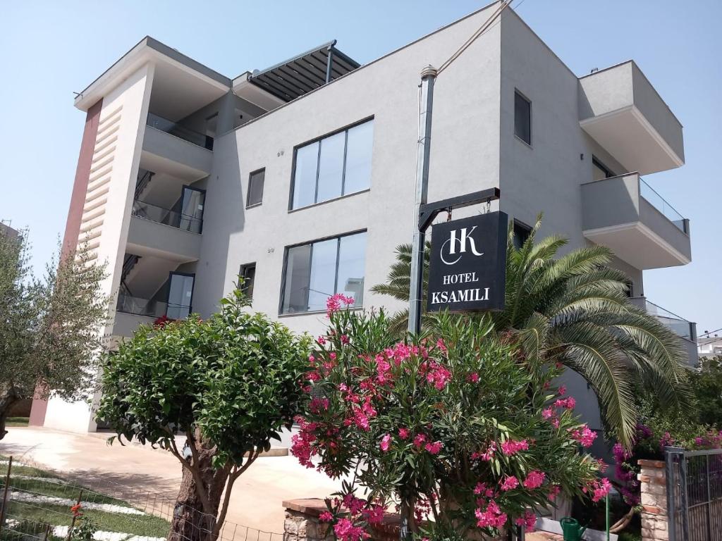 a building with a sign for a hotel with pink flowers at Hotel Ksamili in Ksamil