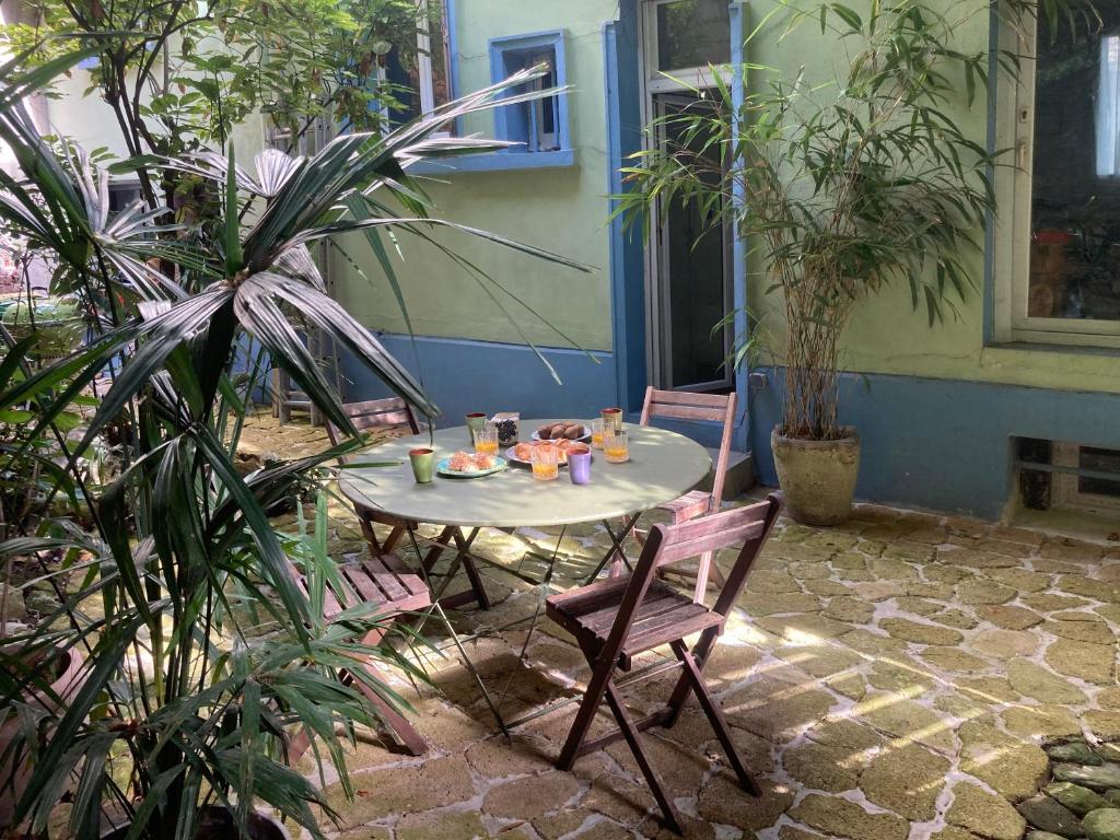 une table et des chaises dans une cour ornée de plantes dans l'établissement Maison avec jardin, à Paris