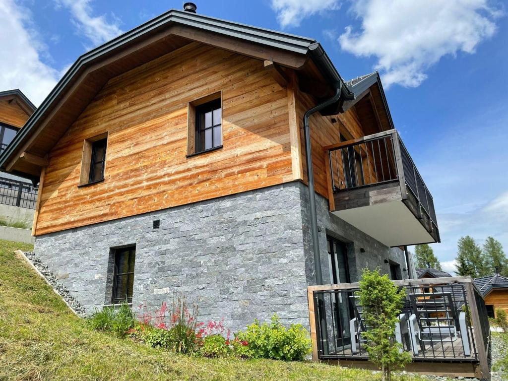 une maison avec un toit en bois et un balcon dans l'établissement Tomtegl-Bergchalet-No-2-mit-Privatsauna-Infinitypool-Kamin-Fitnessraum-1500m-Seehoehe, à Hochrindl