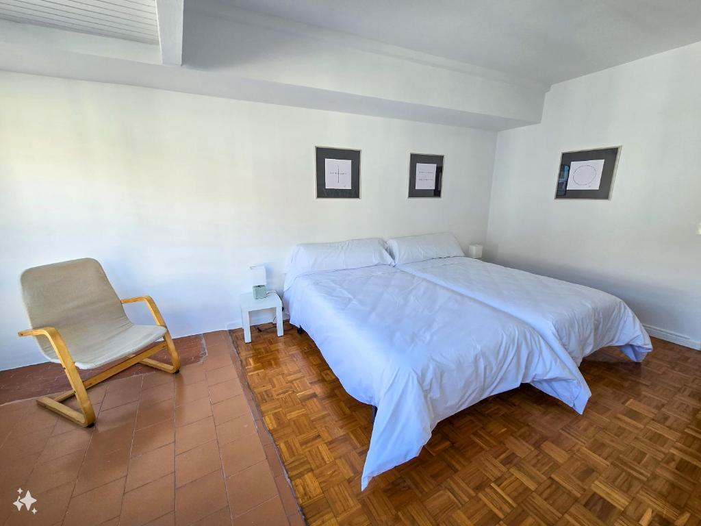 Un dormitorio blanco con una cama y una silla. en Acogedor Apartamento, en Vilagarcía de Arousa