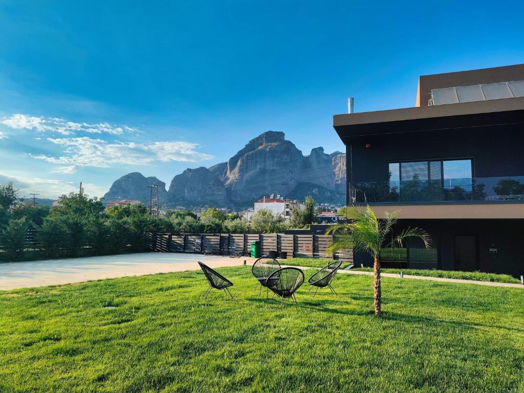 two chairs in the grass in front of a house at Meteora Smart Suites in Kalabaka
