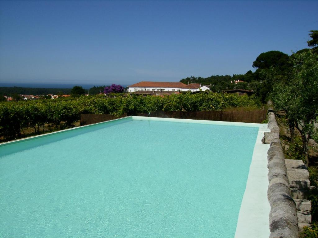 una piscina azul con una casa en el fondo en Quinta do Paco d'Anha, en Viana do Castelo