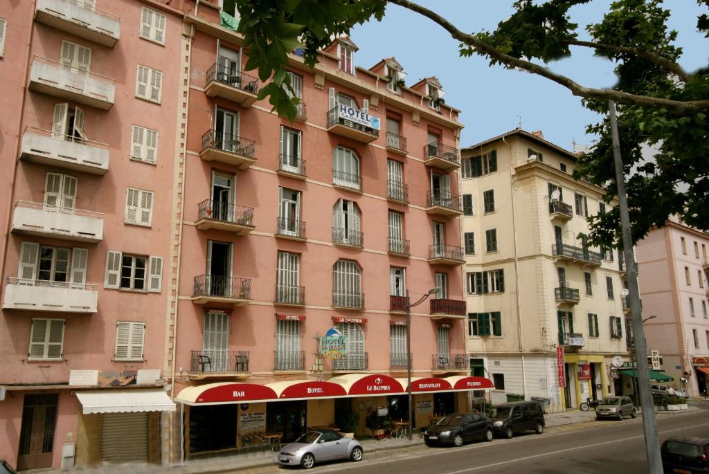 a pink building with cars parked in front of it at Hotel le Dauphin in Ajaccio