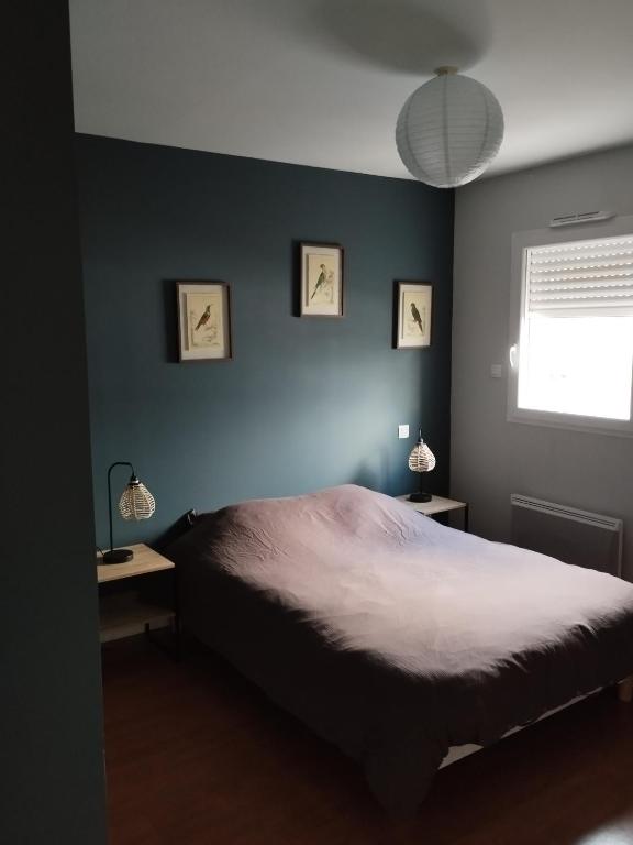une chambre avec un lit et un mur bleu dans l'établissement Maison Centre bourg, à Nort-sur-Erdre