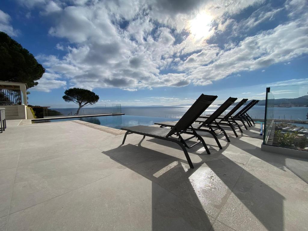- une rangée de chaises assises sur une terrasse donnant sur l'eau dans l'établissement La Renarde, au Lavandou