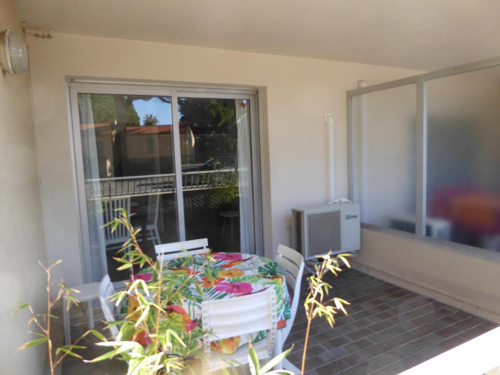 un balcon avec une table, des chaises et une fenêtre dans l'établissement Studio port Hyères 200m mer parking privé, à Hyères