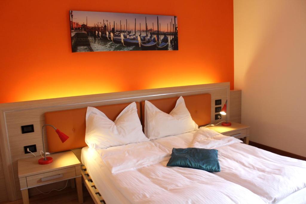 1 dormitorio con cama blanca y pared de color naranja en Ely'S Residence en Romano D'Ezzelino