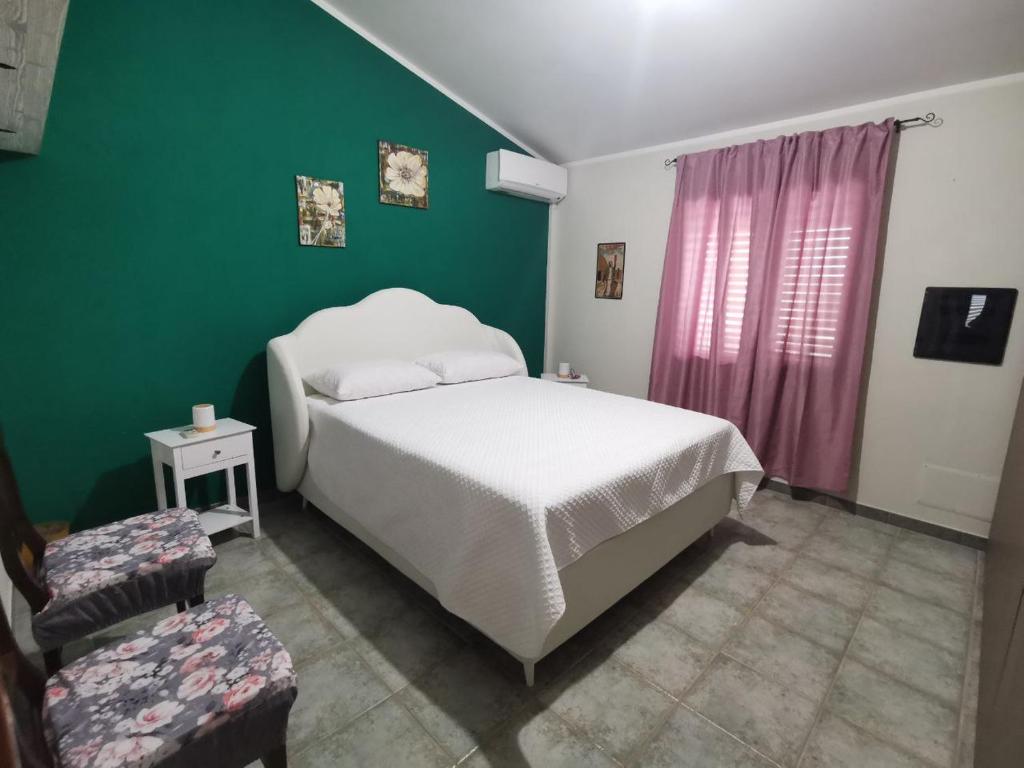 a bedroom with a white bed and a green wall at Appartamento le Magnolie in Decimomannu