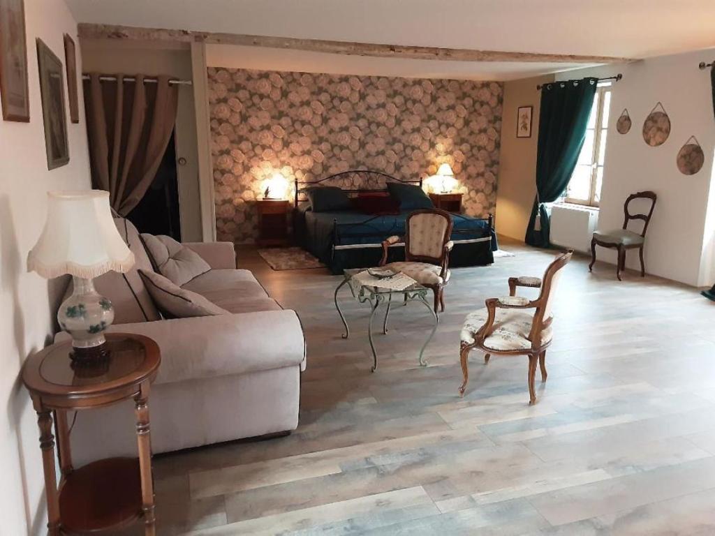 a living room with a couch and a table and chairs at La maison des Roses in Saint-Jodard