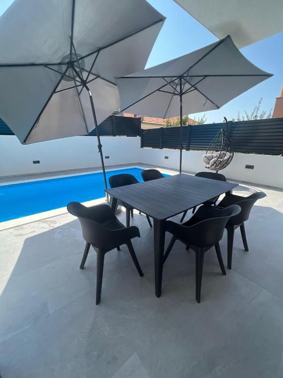 a table and chairs with umbrellas on a patio at Residence Doli Pool in Vrsi
