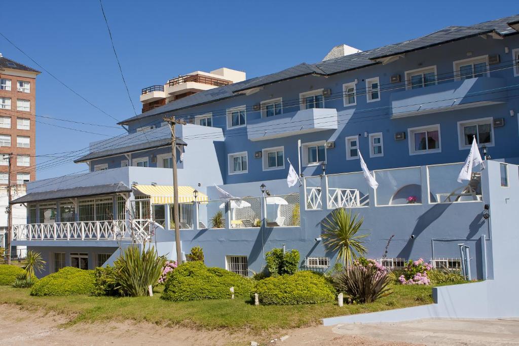 un gran edificio azul con un balcón blanco en Suites Mirage en Pinamar