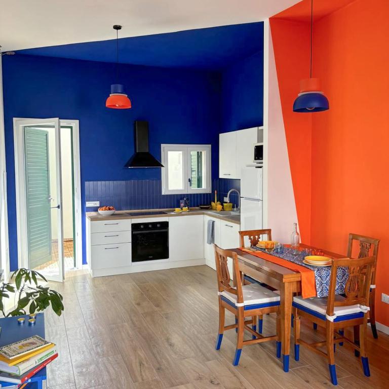 a kitchen with blue and orange walls and a table and chairs at Casa Giù in Cecina
