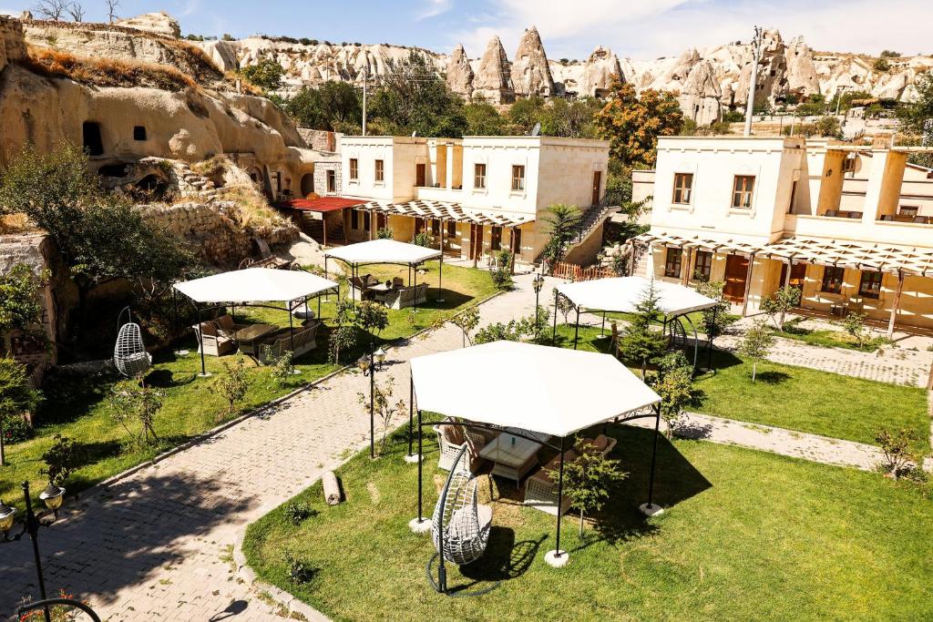 Un lugar al aire libre con sombrillas blancas y una montaña. en Cappadocia Empire Cave Hotel, en Göreme