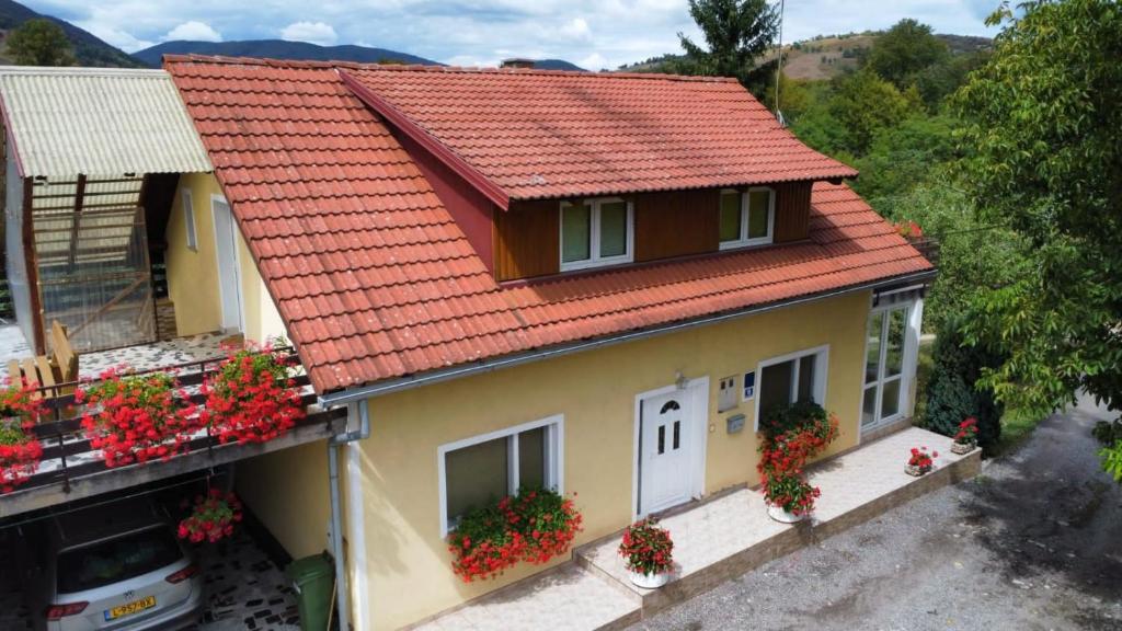 una casa con un tetto rosso e dei fiori di Apartman Majetić a Seliste Dreznicko