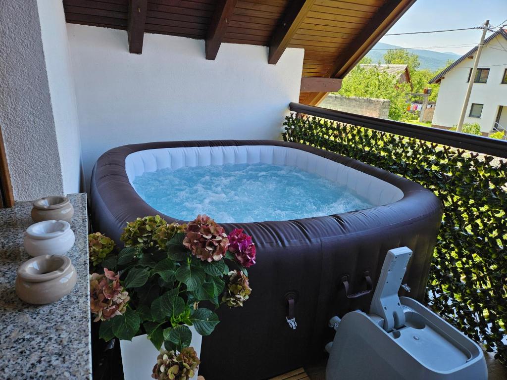a hot tub on a balcony with flowers at Apartment Majetić in Gornji Vaganac