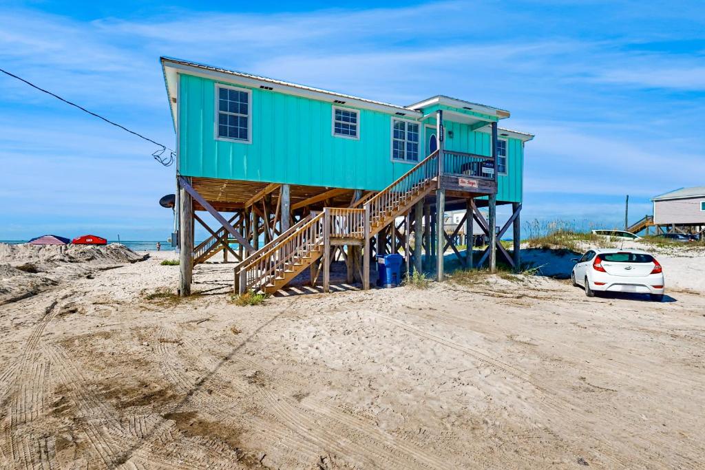 a house on the beach with a car parked next to it at Seascape in Dauphin Island
