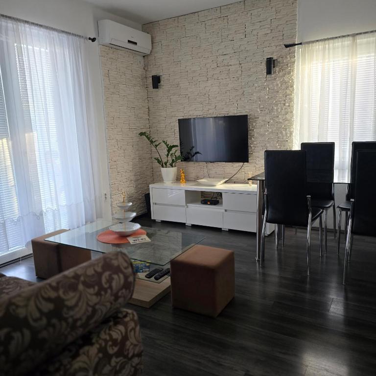a living room with a tv and a table and chairs at Apartment Djordje Budva-Jaz in Kukaljevina