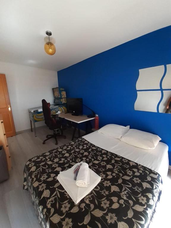Cette chambre comprend un lit avec un mur bleu et un bureau. dans l'établissement Panoramique sur la baie de la ciotat, à La Ciotat