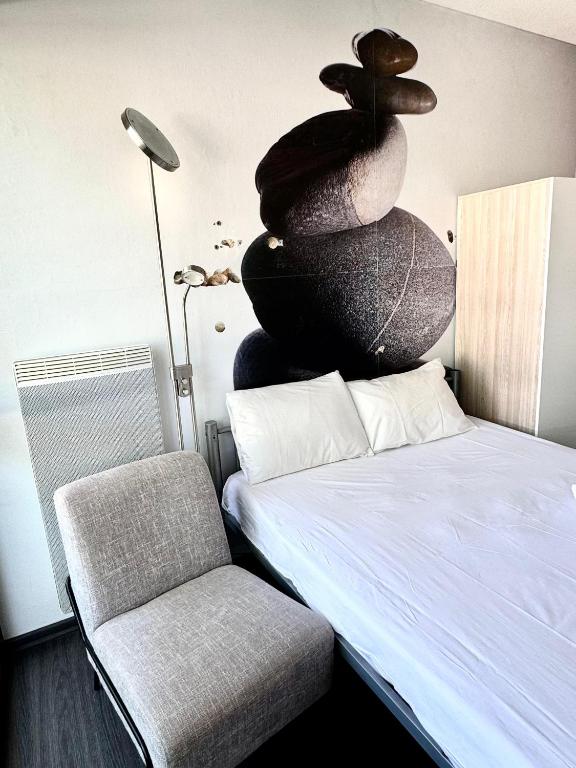 une pièce avec un lit, une chaise et une pile de pierres dans l'établissement Appartement La Rochelle, à La Rochelle