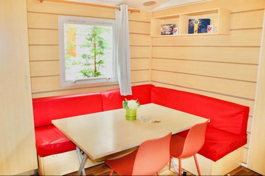 une salle à manger avec une table blanche et des chaises rouges dans l'établissement Mobil Home Cosy, à Saint-Chéron