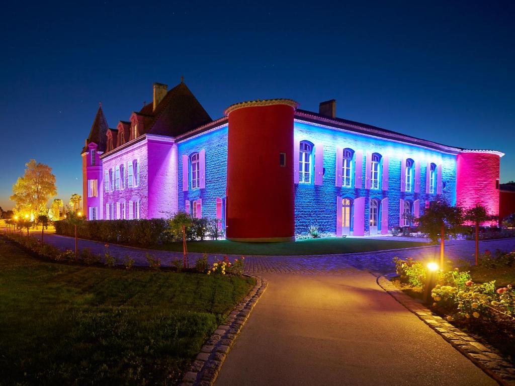 un bâtiment est éclairé en bleu et rose dans l'établissement Le Stelsia Resort, à Saint-Sylvestre-sur-Lot