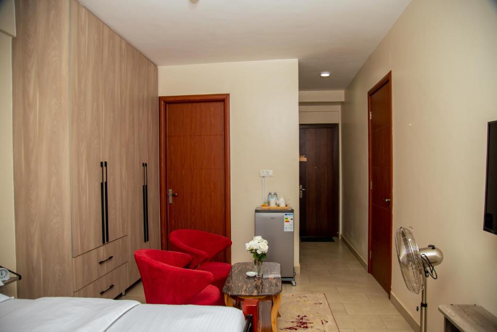Una habitación de hotel con una cama y dos sillas rojas. en Edge Studio Apartment, en Kampala