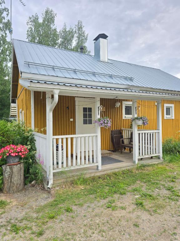 a yellow house with a porch and a white fence at Vanha myllärin torppa in Sulkava
