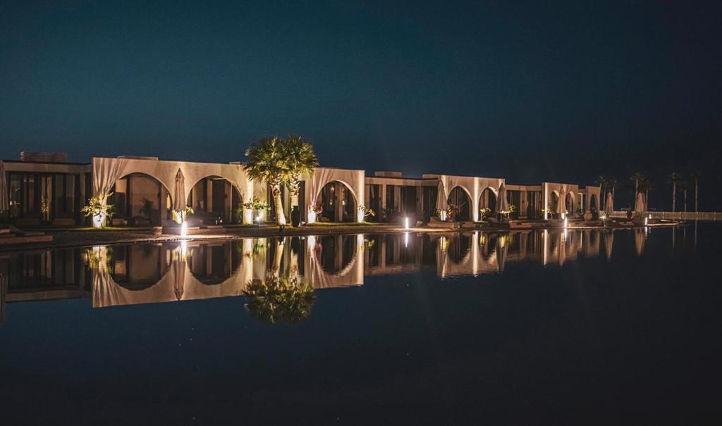 a house with a reflection in the water at night at Le sidi cabins Hacienda Bay in El Alamein