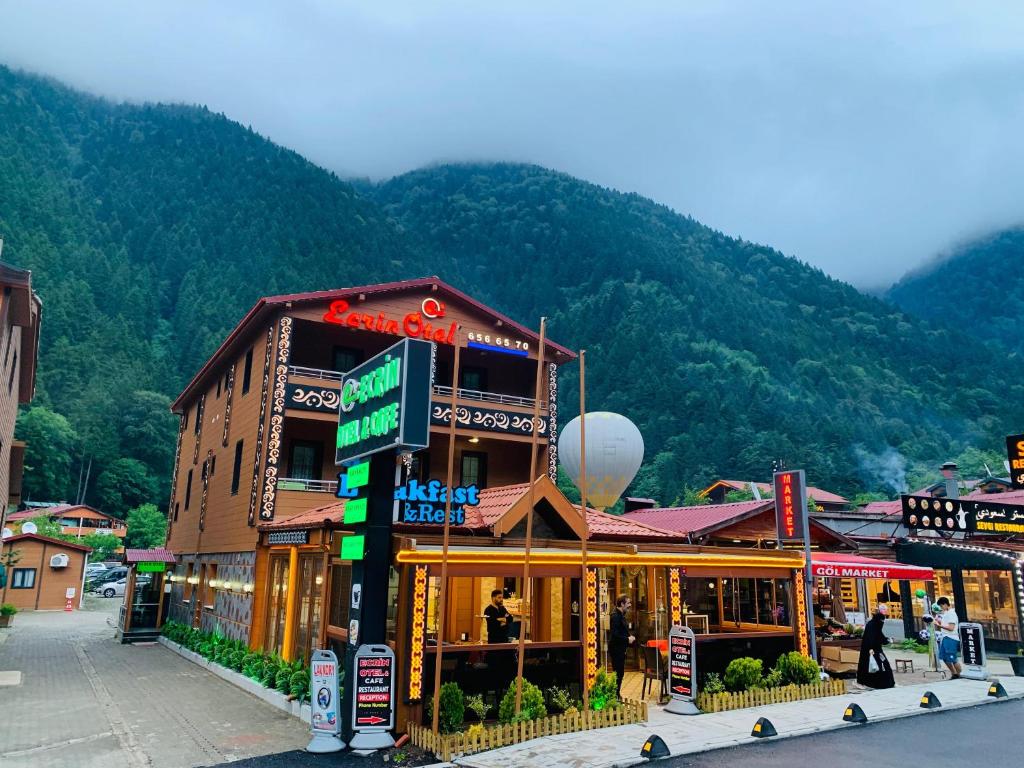 a building on a street with a mountain in the background at ECRİN OTEL in Uzungöl