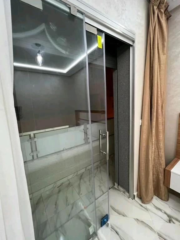 een glazen douche in de badkamer met een spiegel bij مارتيل حي احريق in Martil