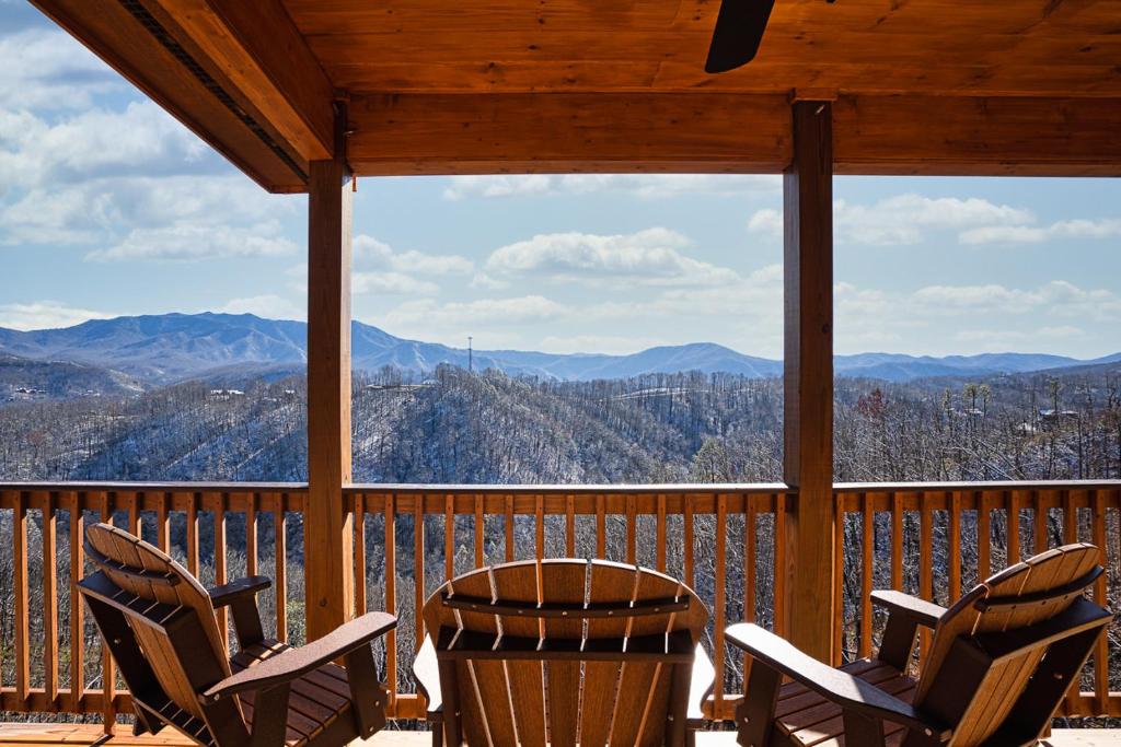 three chairs on a porch with a view of mountains at The Bear and Trout by Stony Brook Cabins in Gatlinburg