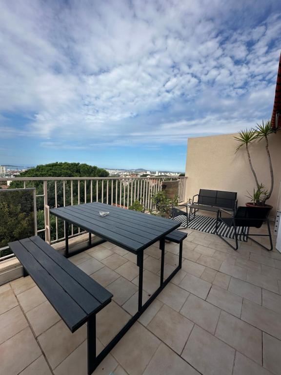 une table de pique-nique et des bancs sur une terrasse avec balcon dans l'établissement T4 avec Terrasse et Garage Privé, à Toulon