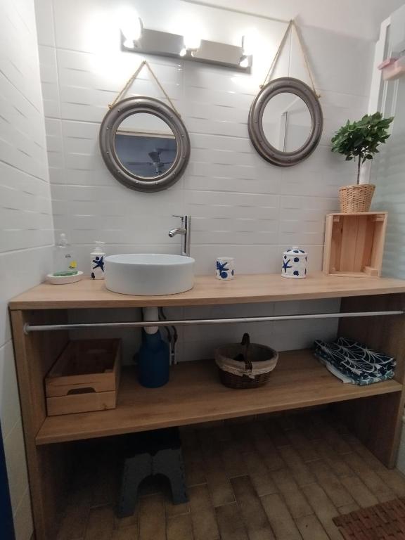 une salle de bain avec un lavabo et deux miroirs au mur dans l'établissement L'effet mer, au Grau-du-Roi
