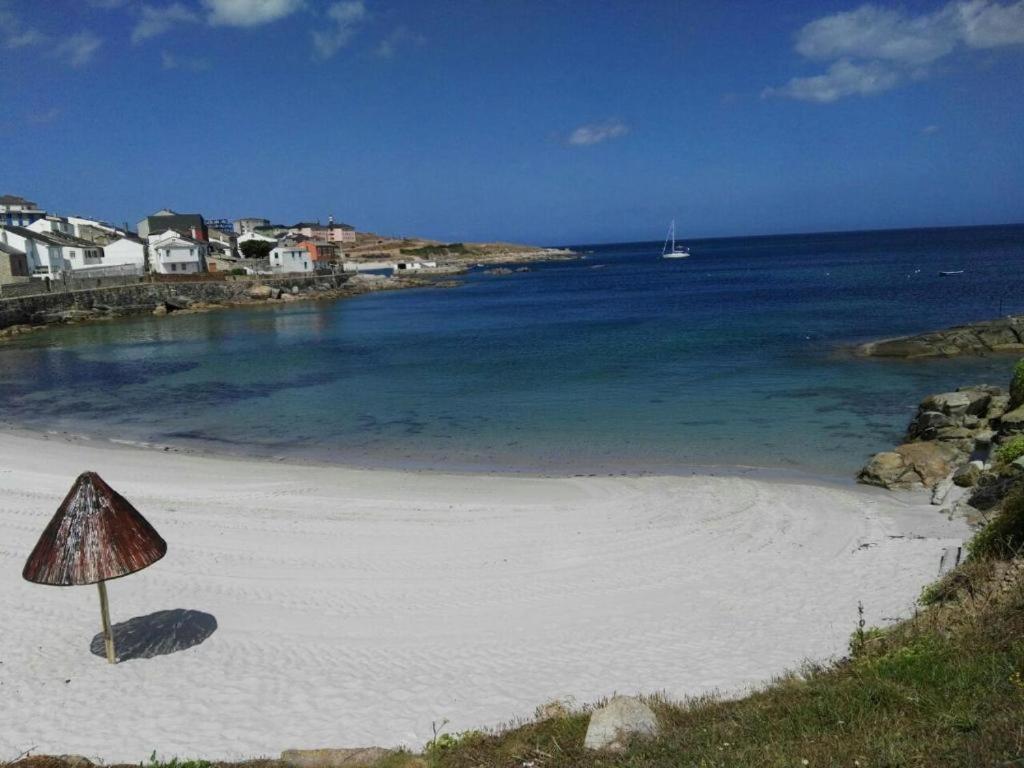 a beach with a cone shaped umbrella on the sand at Casa duples junto playa Cubelas in San Ciprián