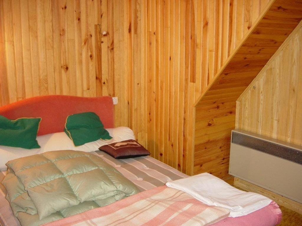 ein Schlafzimmer mit einem Bett in einem Holzzimmer in der Unterkunft Chalet in Bolquere