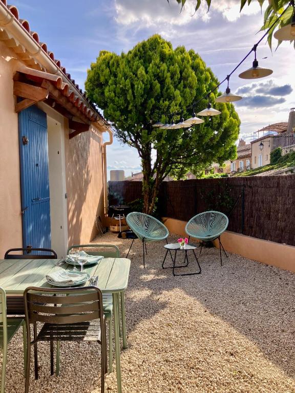 un patio avec des tables et des chaises et un arbre dans l'établissement La maison des cerisiers, à Bédoin
