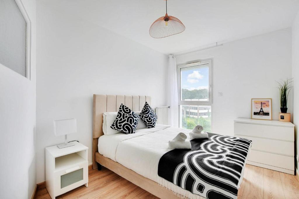 Dormitorio blanco con cama grande con almohadas blancas y negras en ParisCharm, en Pantin