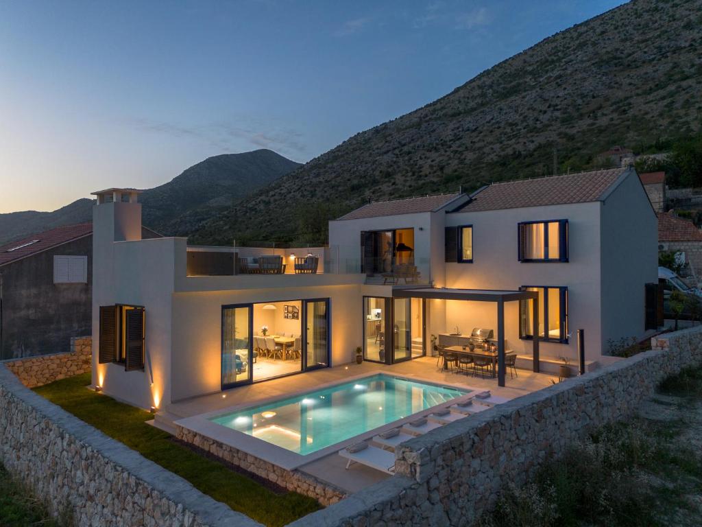 a villa with a swimming pool in front of a house at Villa La Miel in Donji Majkovi