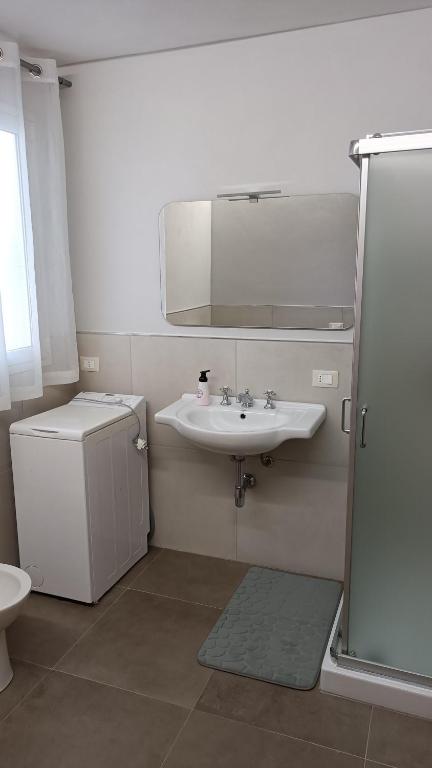 biała łazienka z umywalką i lustrem w obiekcie Santa Genoveffa Apartment w Trapani