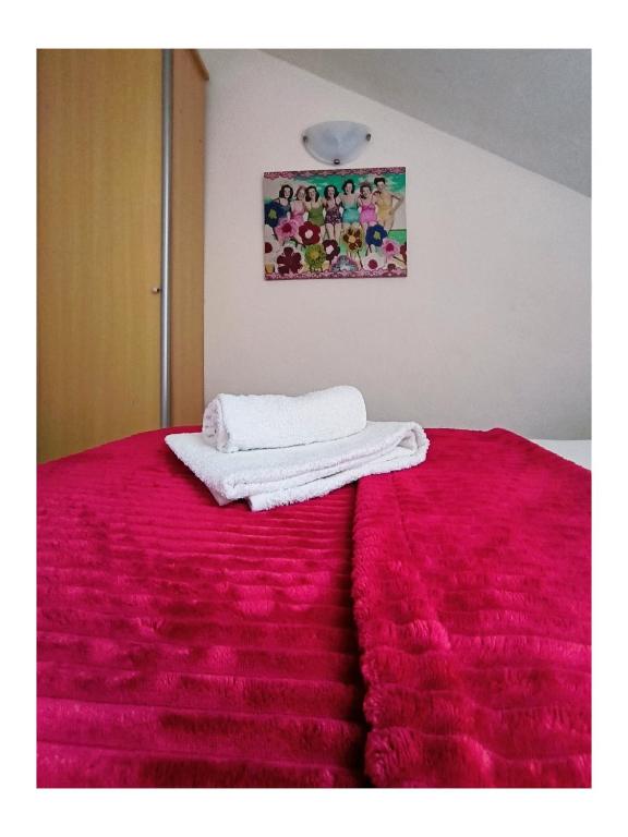 a bed with a red blanket and two towels on it at Apartments Senko in Trpanj