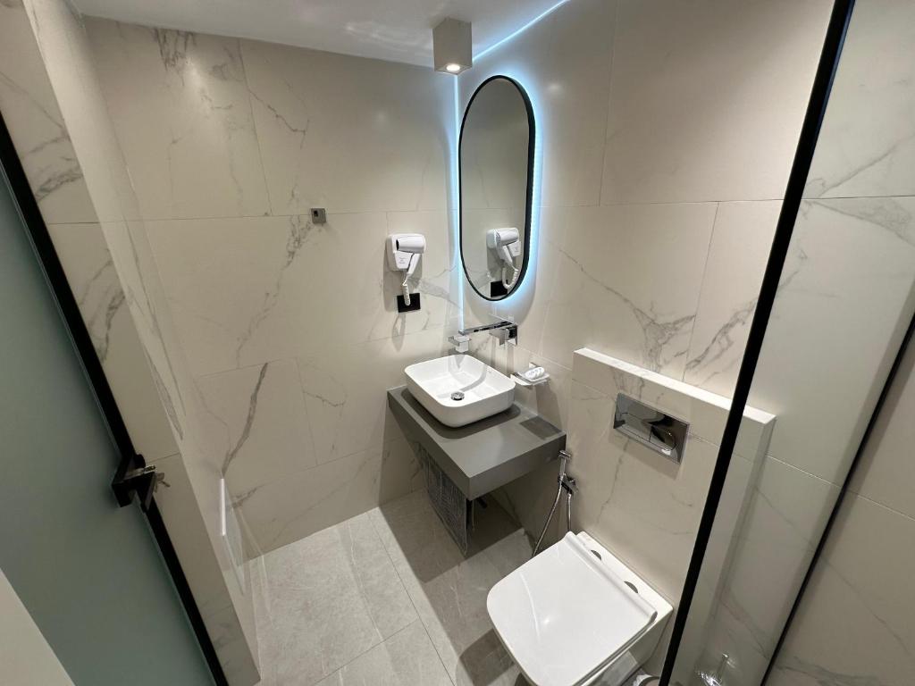 a white bathroom with a sink and a mirror at Vila Olserd Shehu in Ksamil