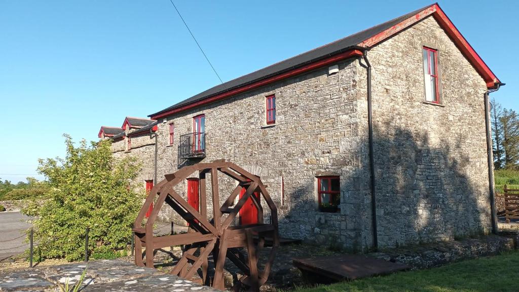un vecchio edificio in mattoni con un cancello in legno di fronte di The Old Mill, Kilcorkey Bellanagare, Castlerea, County Roscommon - West of Ireland - House 2 a Bellanagare