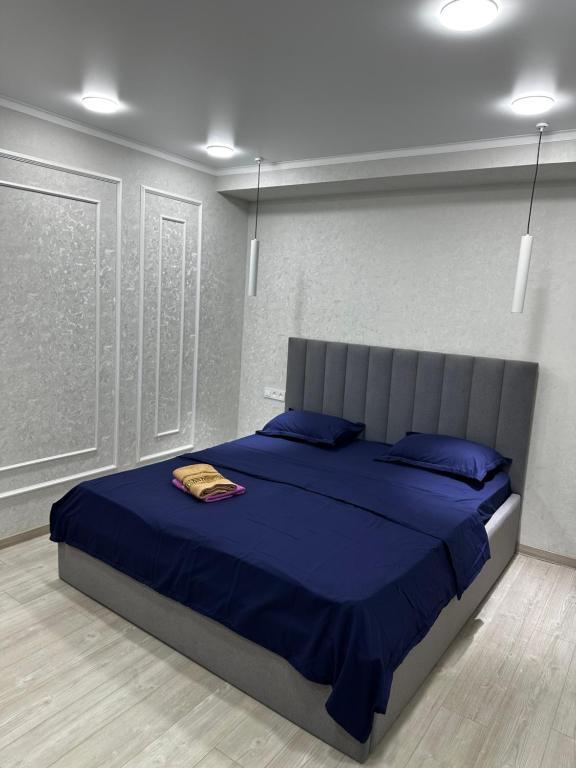 a bedroom with a bed with blue sheets and blue pillows at 1 комнатная квартира Lux класса в центре Шымкента in Shymkent
