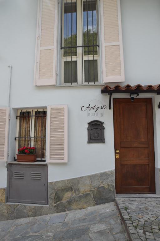 a white house with a door and a window at An tij slè - Nel cuore del borgo in Guarene