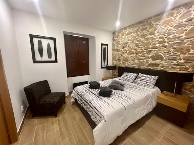 a bedroom with a large bed and a chair at Casa de Pedra in Pedrógão Grande